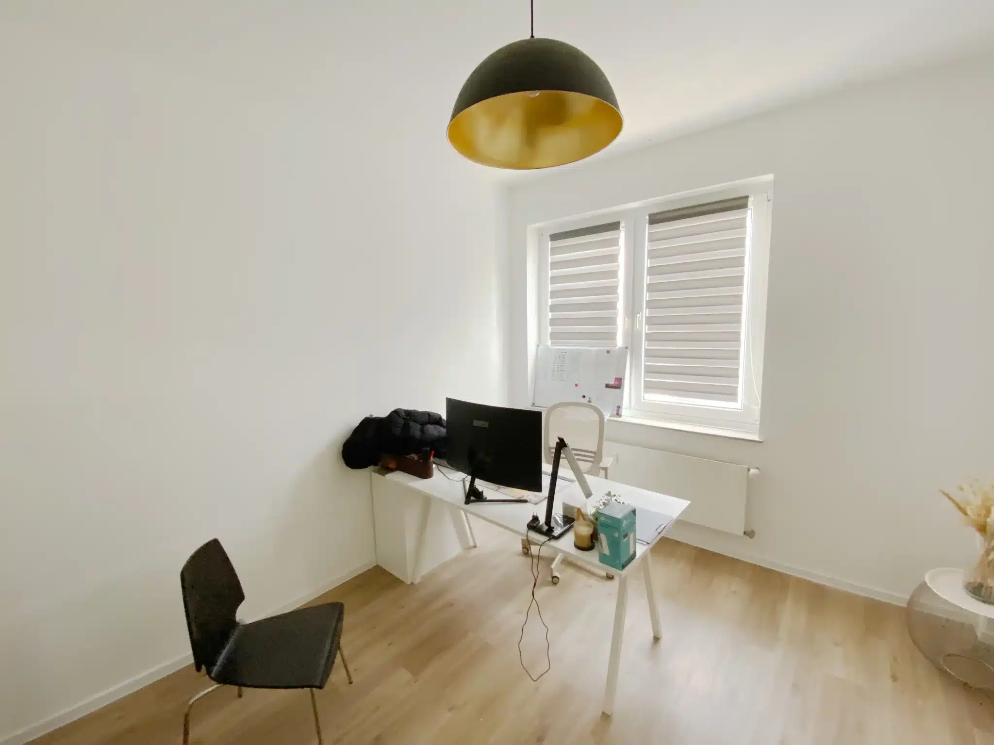 Moderner kleiner Büroraum mit Schreibtisch, Stuhl und großem Fenster.