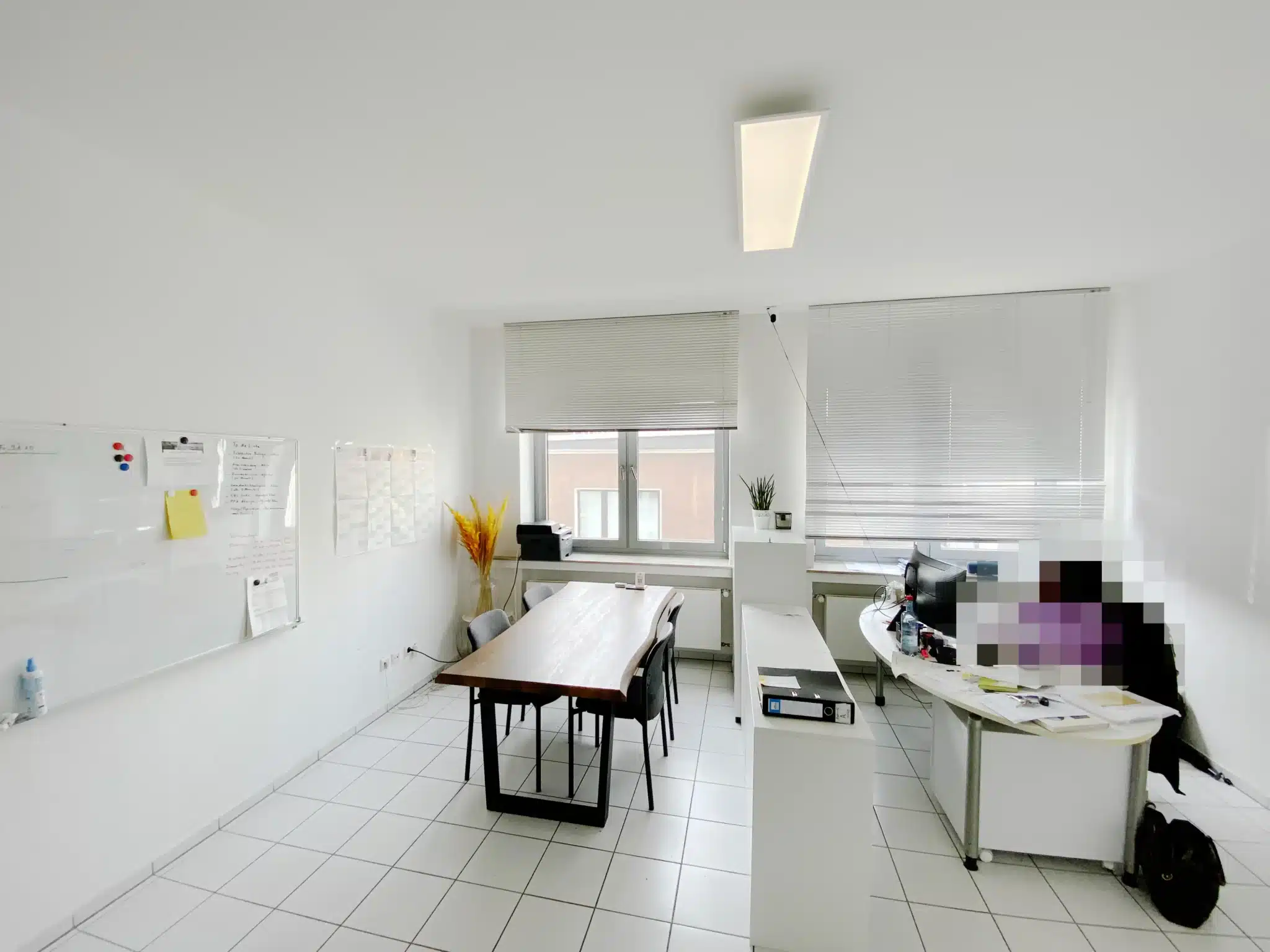 Büroraum mit großem Konferenztisch, Whiteboards und eingerichteten Arbeitsplätzen.